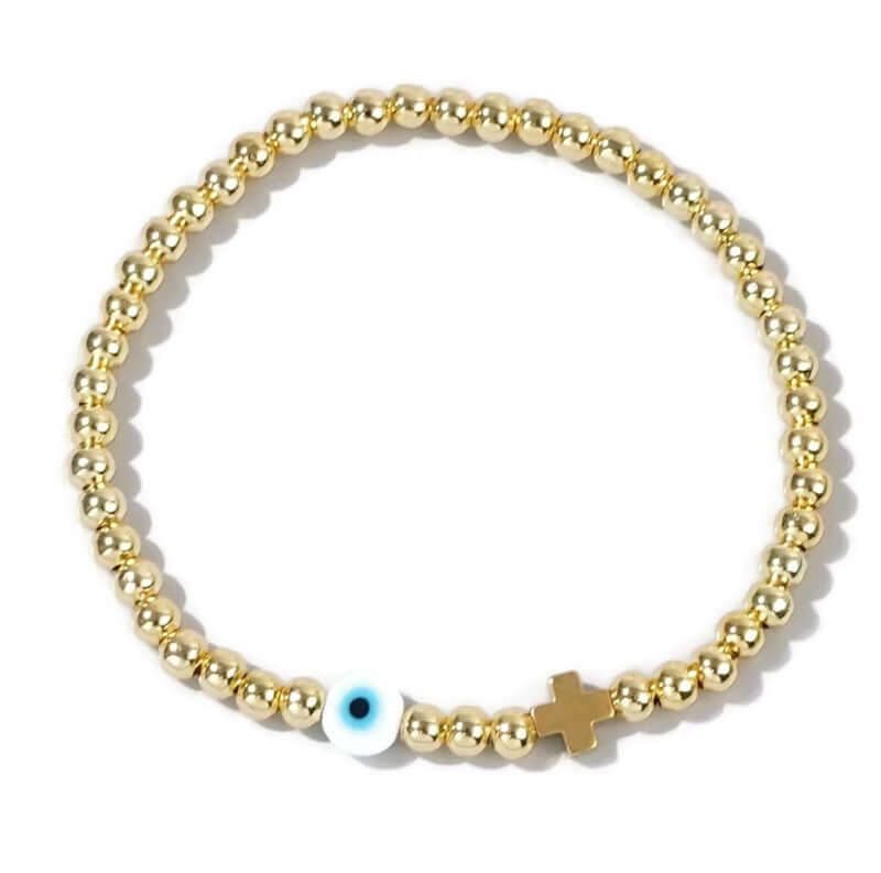 Gold beaded bracelet with an evil eye and cross charm on a white background