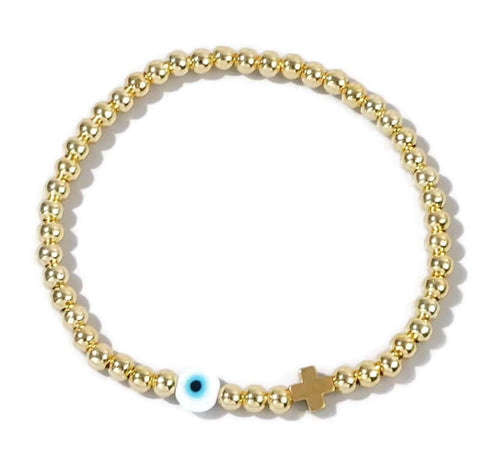 Gold beaded bracelet with an evil eye and cross charm on a white background