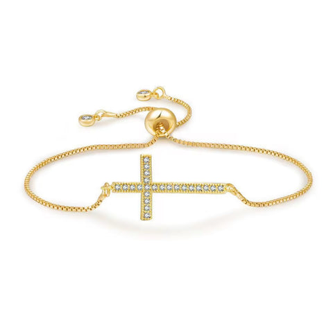 Gold bracelet with a sideways cross design on a white background with cubic zirconia adjustable to wrist