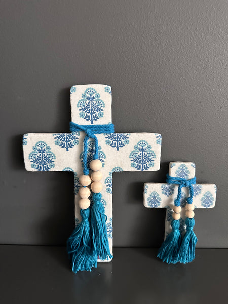 Decorative cross with blue patterns and tassels on a dark surface and gray background